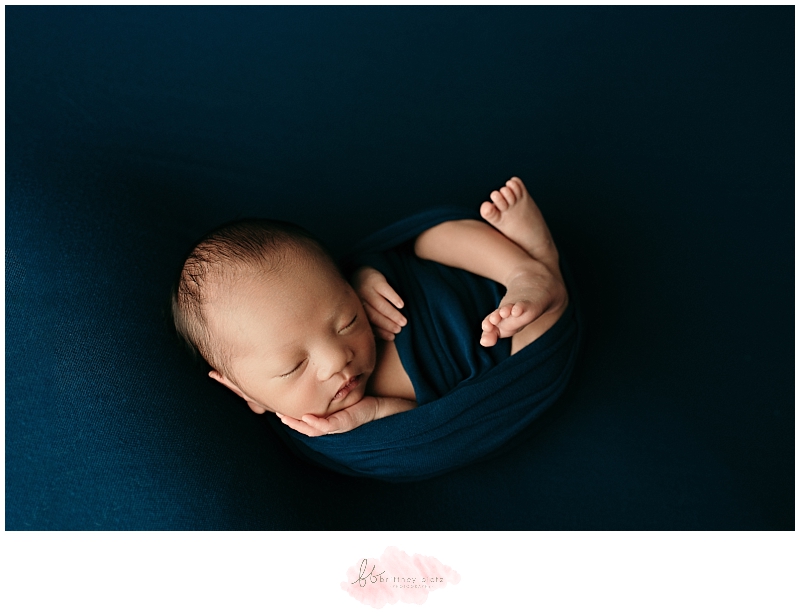 Baby boy on back wrapped in blue jewel tone fabric